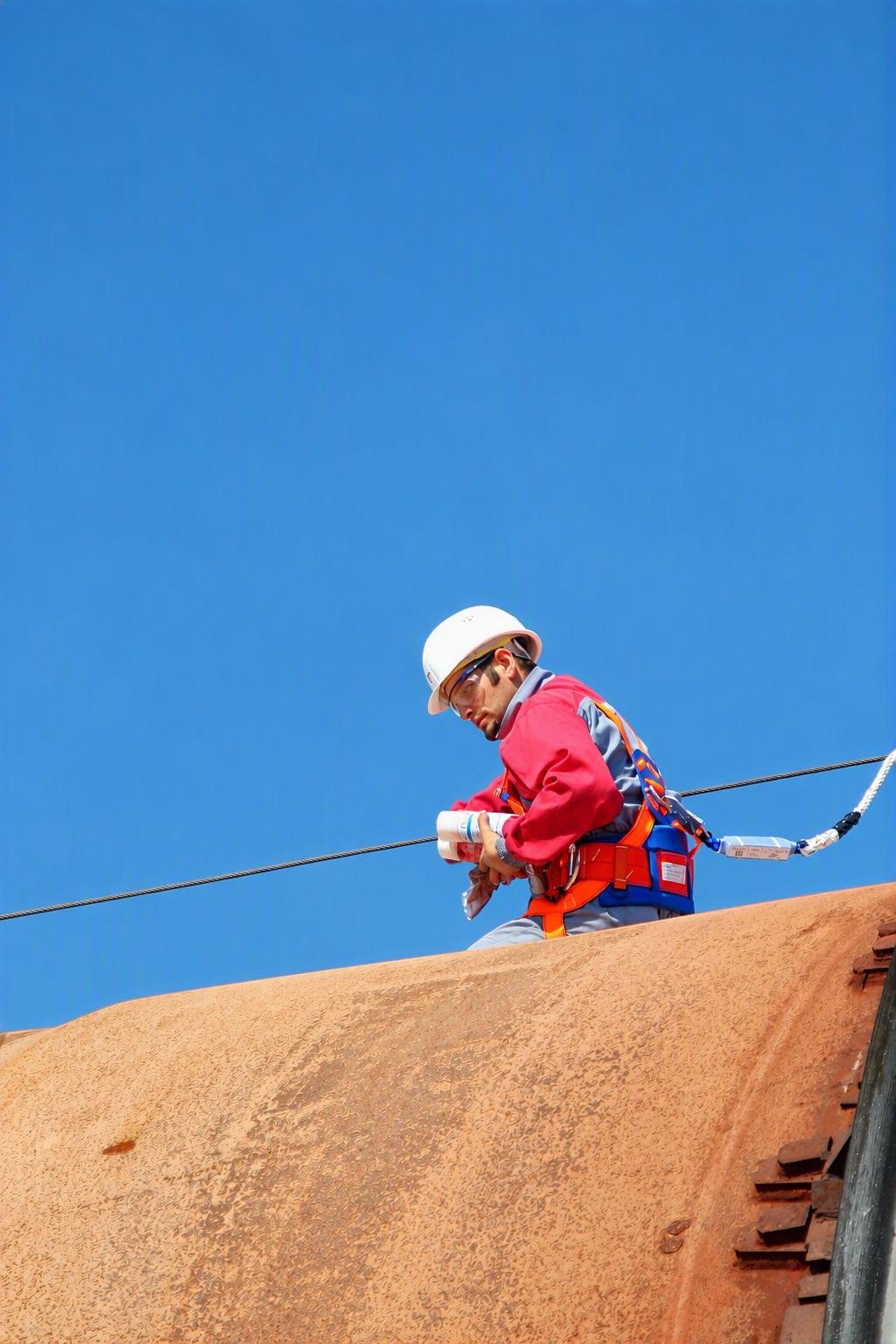 Supervisor harnessed atop industrial kiln equipment during an on-site inspection